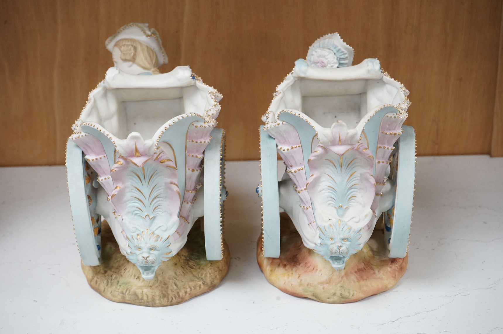 A pair of French coloured biscuit porcelain carriage group centre pieces, 21cm wide